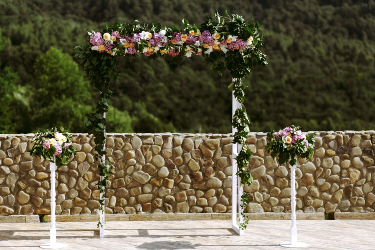 Luxury wedding arch with lush leaves, delicate roses and purple hydrangea outdoors. Wedding floristry